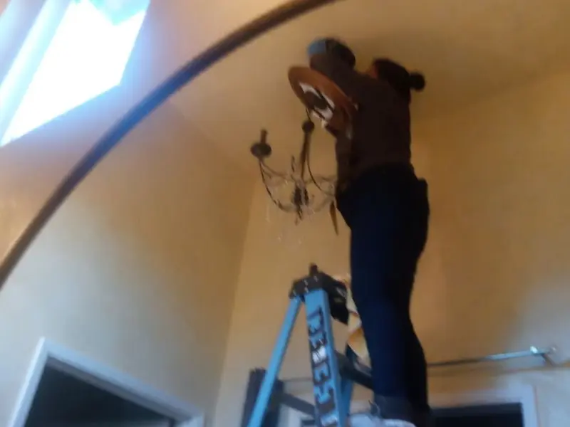 Electrician installing a chandelier in a Englewood residence